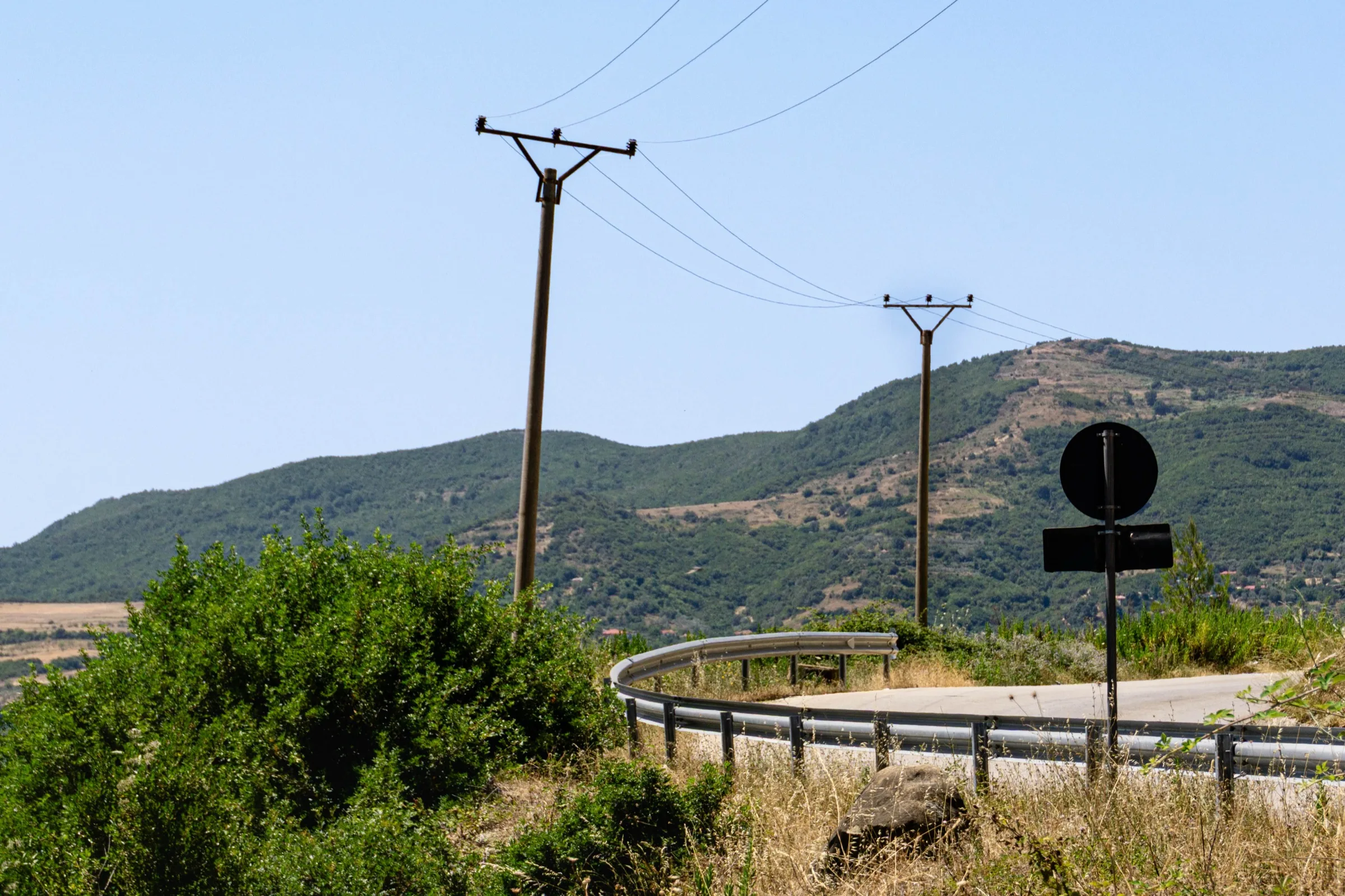 Een kronkelende bergweg met elektriciteitspalen