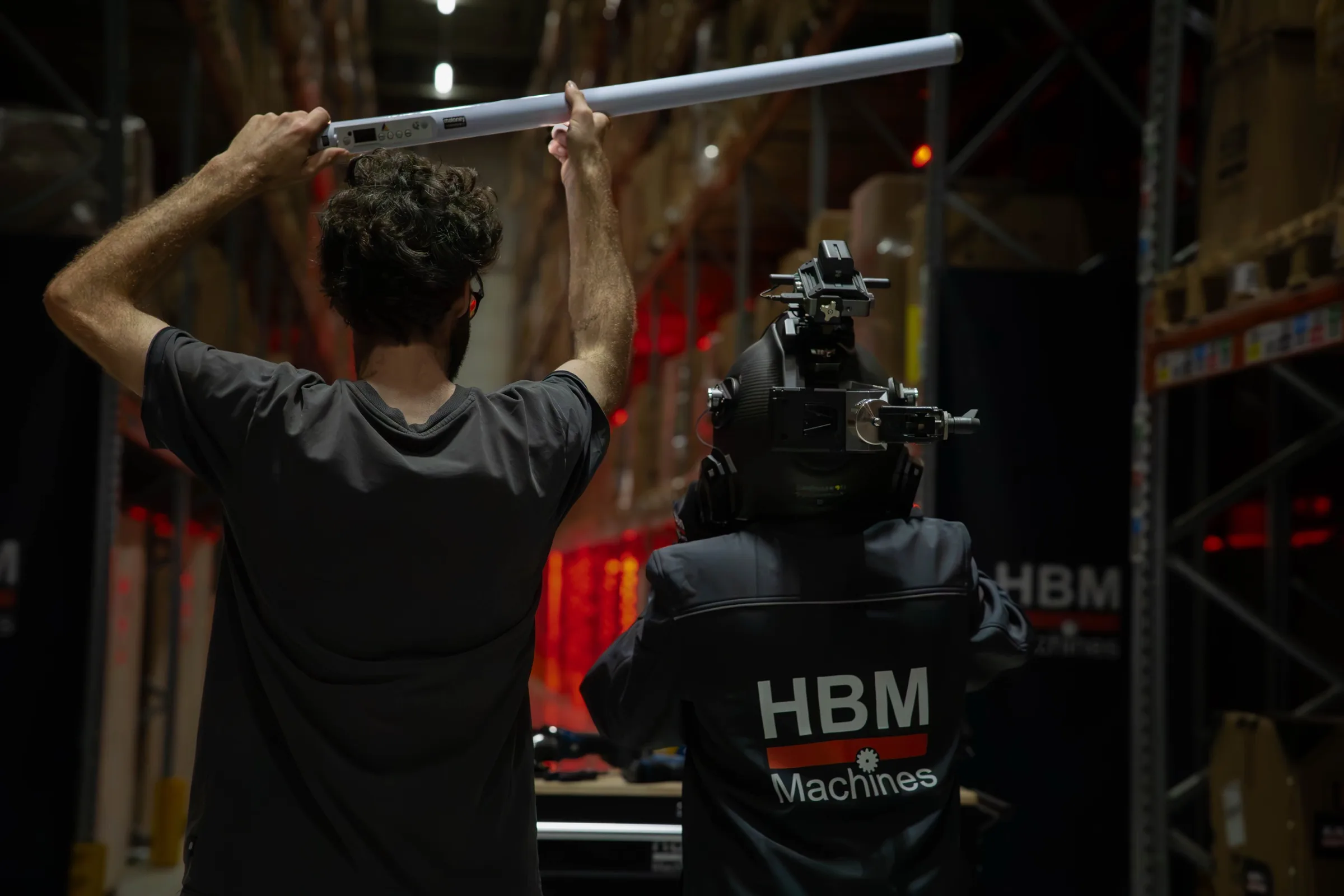 Een crewlid tilt een lamp boven de cameraman met helmcamera