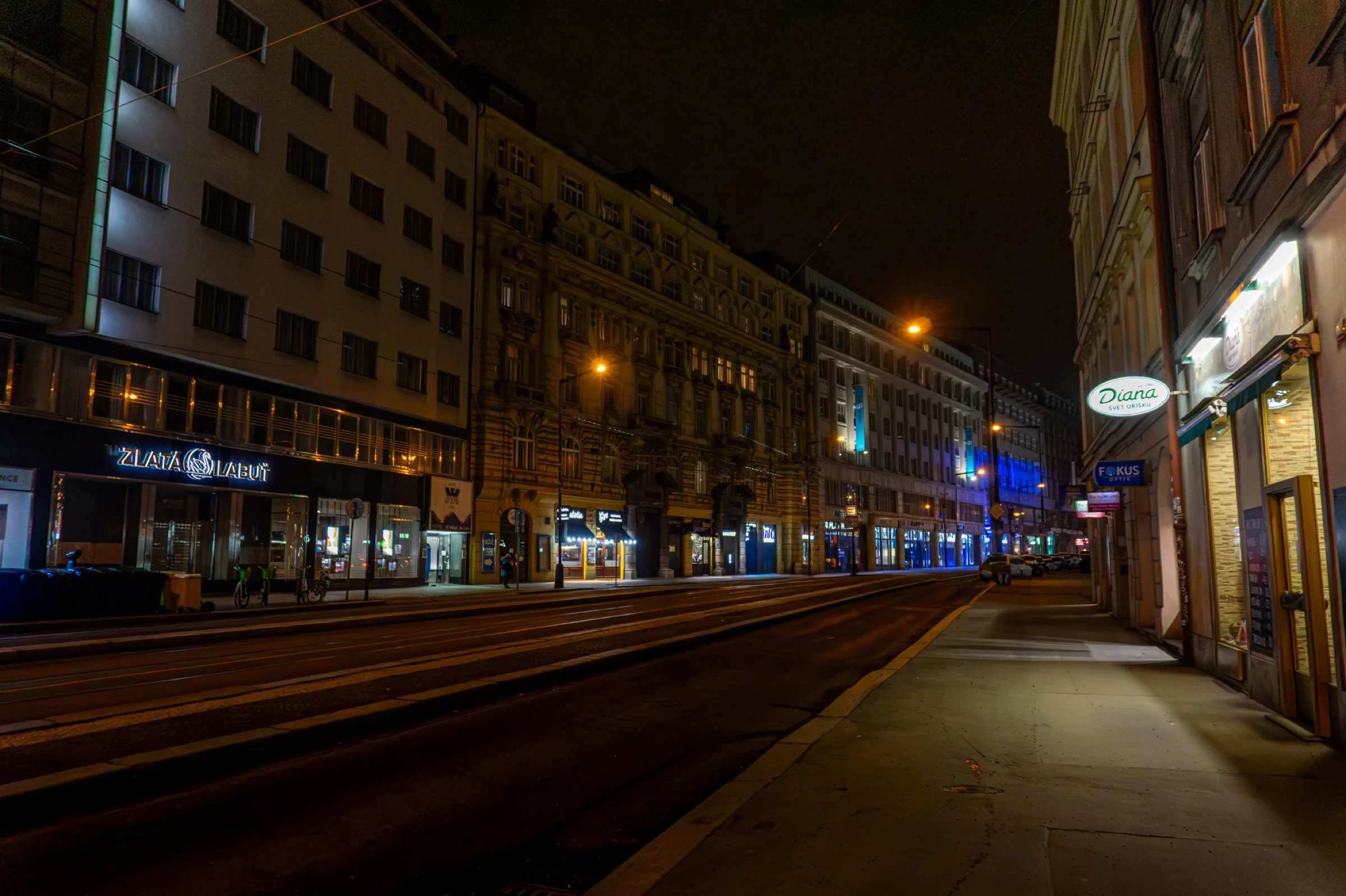 Een lege brede straat bij nacht met verlichte gevels