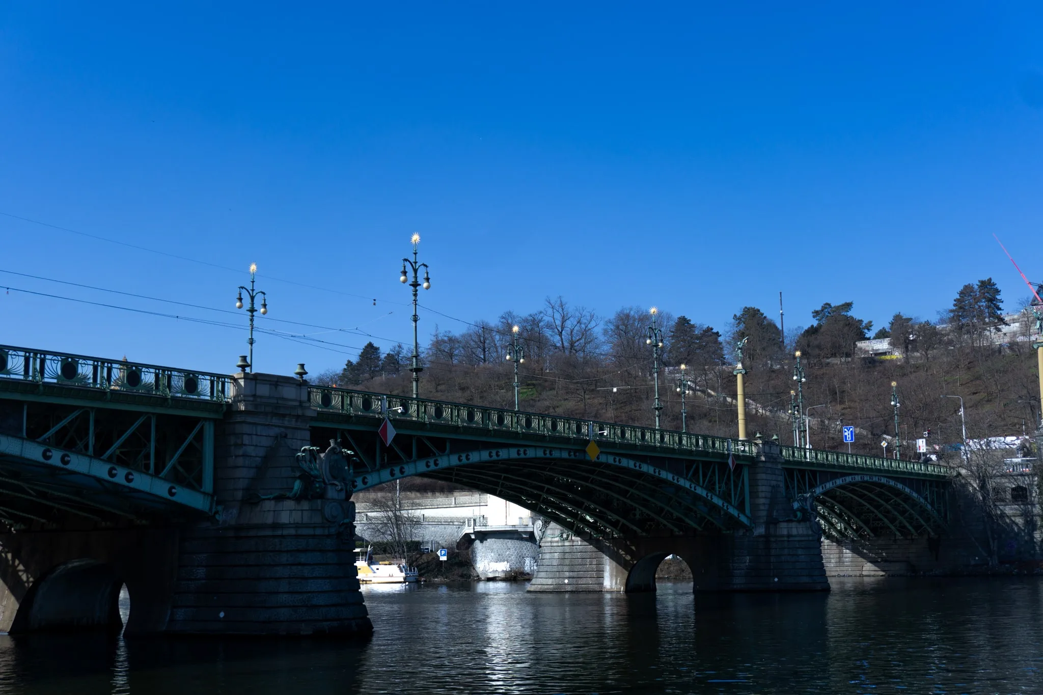 Een ijzeren brug over het water tegen een strakblauwe lucht