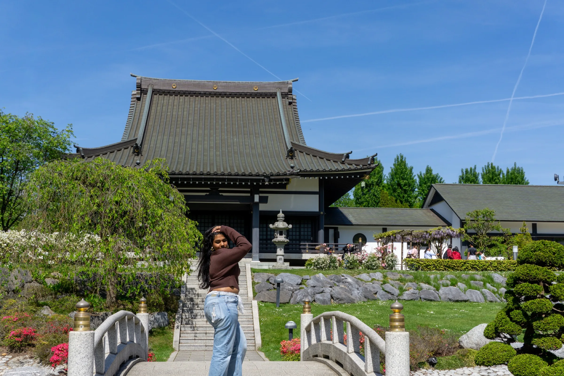 Een vrouw op een stenen bruggetje voor een Japanse tempel