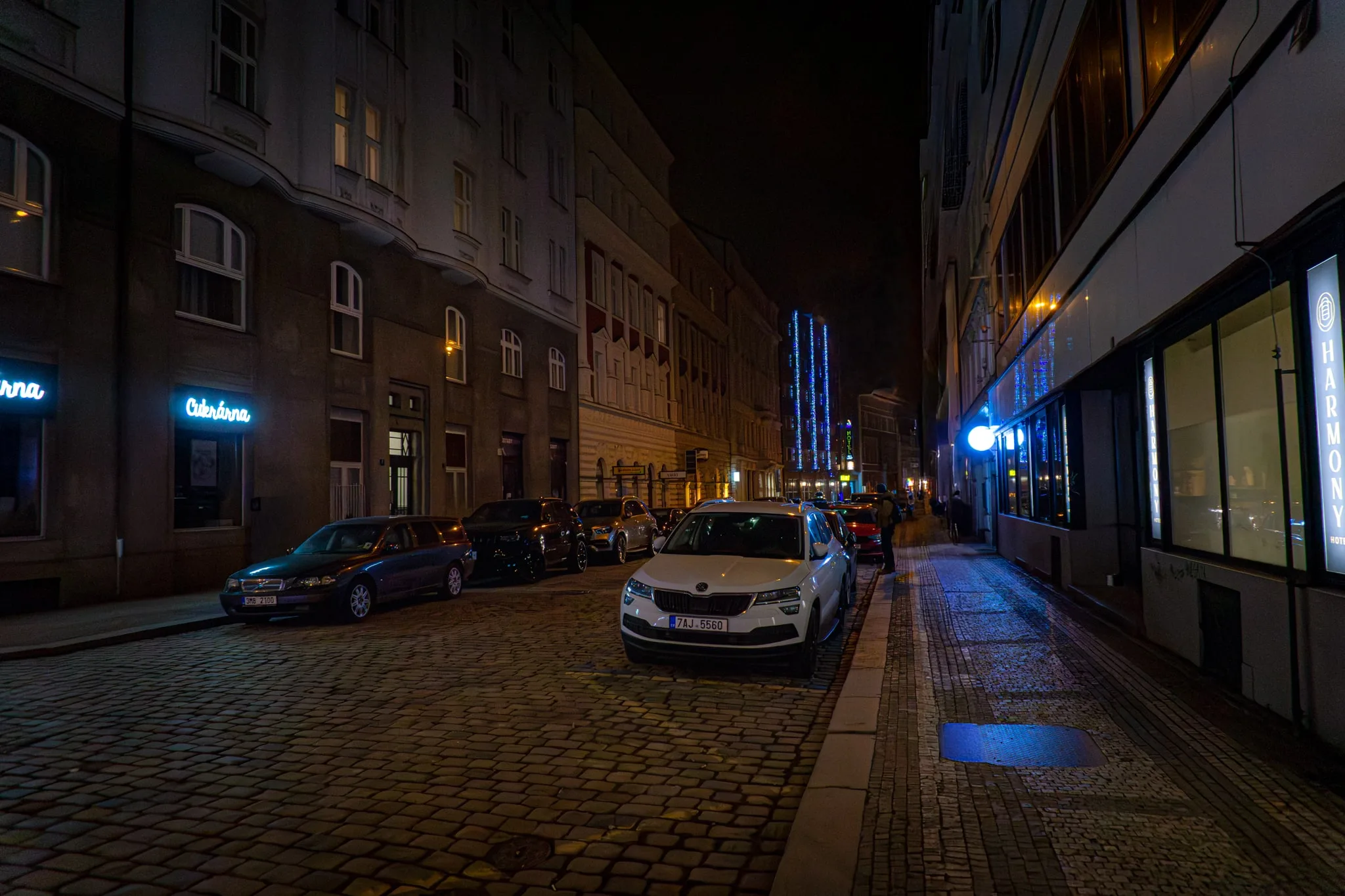 Een lege straat bij nacht met geparkeerde auto’s en straatlicht