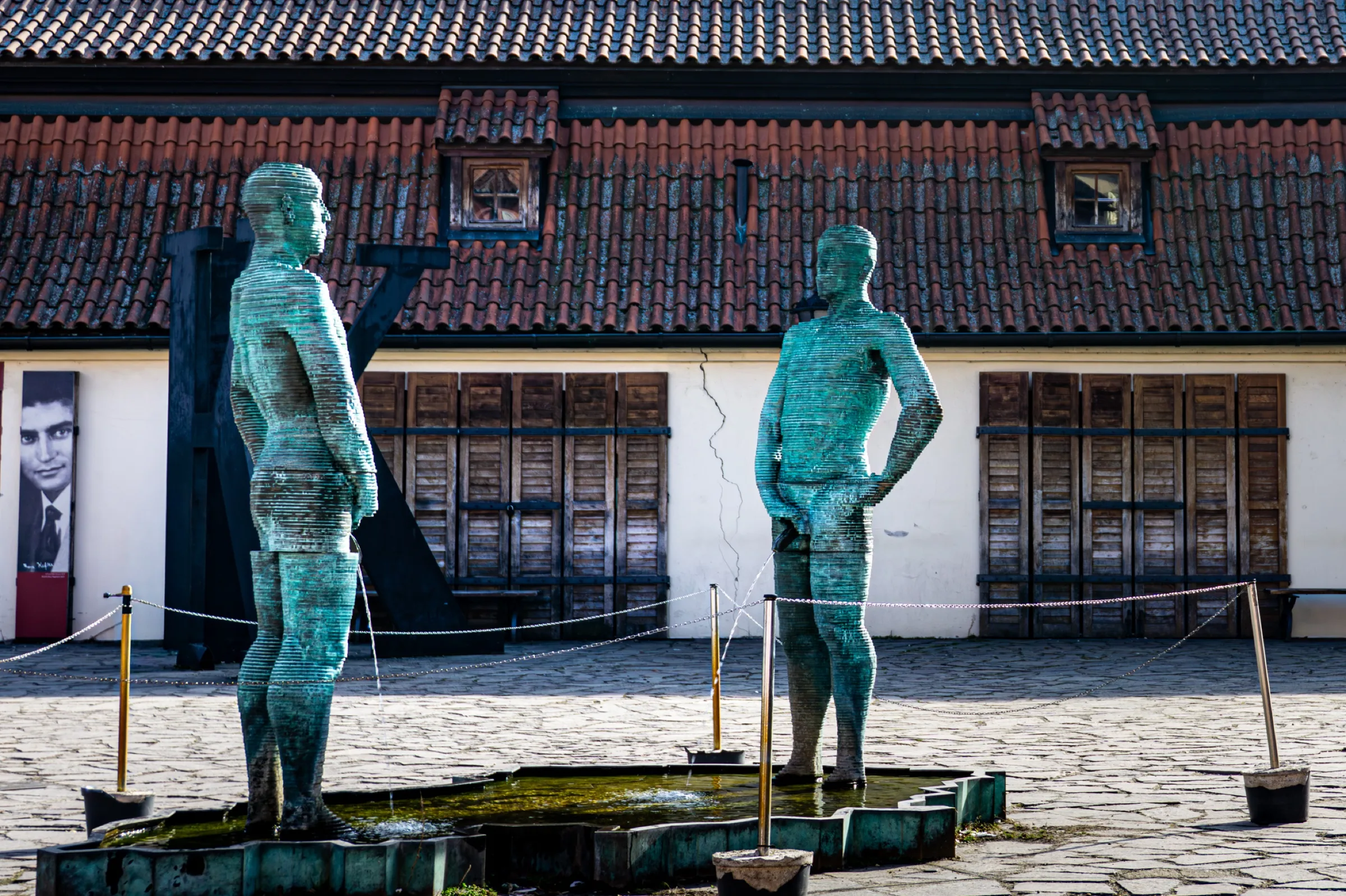 Twee bronzen beelden in een fontein voor een oud gebouw
